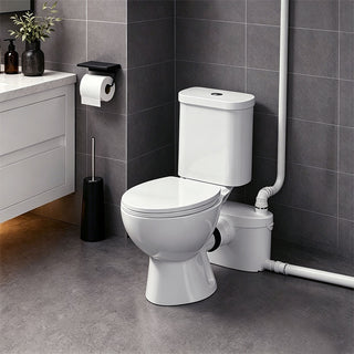 Toilet and pump system in a bathroom with gray tiles and a sink.